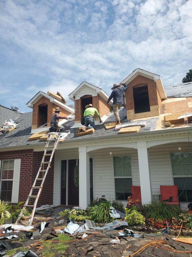 Roofing crew tearing off old shingles around dormers