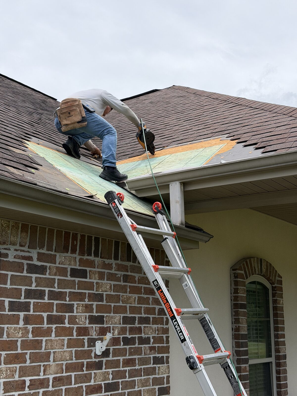 Roofer on a ladder repairing wind damaged shingles in Lake Charles, Louisiana